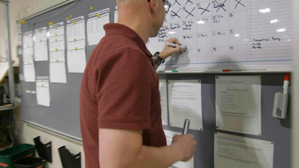Person writing on a whiteboard calendar.