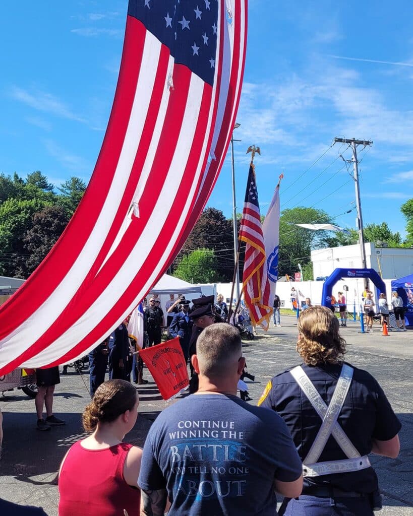 Wire Chasers Return to the Tarentino Strong 5K 2 Parade with flags and spectators present.
